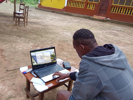 A person doing calculations behind a laptop